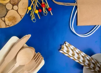 Selbstklebende Fototapeten Disposable wooden cutlery on blue background © artemidovna