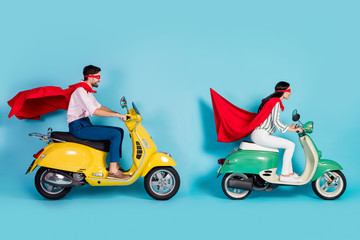 Full length photo of cool lady guy drive sit two vintage moped wear red cape mask rushing road halloween party play super heroes role coat flying air isolated blue color background