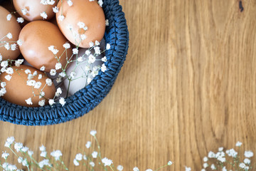 Happy easter! Easter eggs in blue basket on wooden background