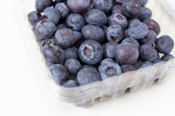 ripe blueberry in a transparent plastic container on a white background