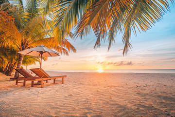Beautiful tropical sunset scenery, two sun beds, loungers, umbrella under palm tree. White sand, sea view with horizon, colorful twilight sky, calmness and relaxation. Inspirational beach resort hotel - obrazy, fototapety, plakaty
