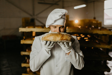 chef sniffs the loaf of a kitchen baker - obrazy, fototapety, plakaty