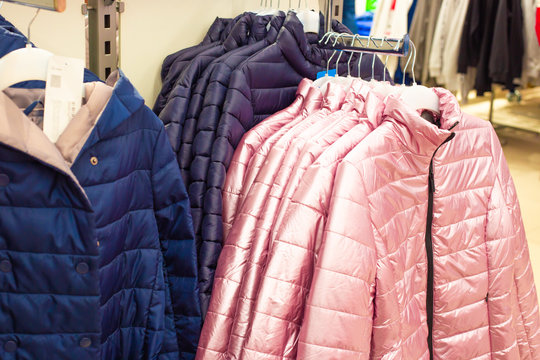 warm demi-season jackets hang on a hanger in a store