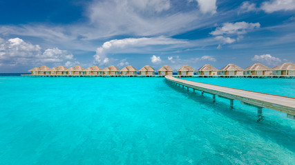 Panoramic landscape of Maldives beach. Tropical panorama, luxury water villa resort with wooden pier or jetty. Luxury travel destination background for summer holiday and vacation concept.