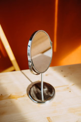 table mirror on a background of an orange wall with sunbeams.
