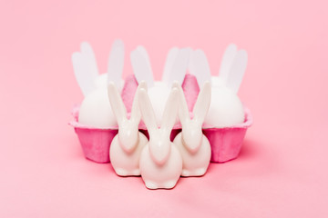 Selective focus of decorative easter bunnies with egg tray on pink background