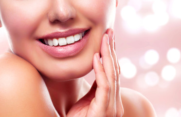 Obraz premium Closeup shot of young beautiful woman face portrait with healthy skin. Pretty girl smiling to you on an abstract background with blurred lights