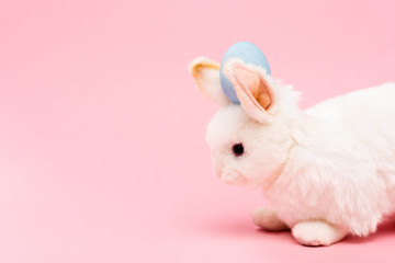 Decorative bunny with blue easter egg on pink background