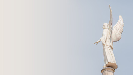 Statue of winged angel with a protecting hand at Evangelical church Saint Nikolai at sunset with...