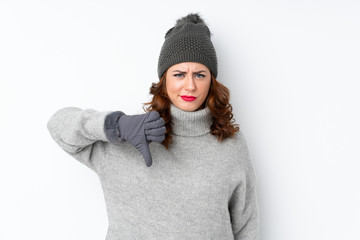 Young Russian woman with winter hat over isolated white background showing thumb down sign