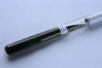 Trivalent green chromium oxide in a test tube with the formula, on a white background. A crystalline, highly refractory substance used in the glass industry.