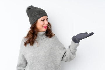 Young Russian woman with winter hat over isolated white background holding copyspace imaginary on the palm