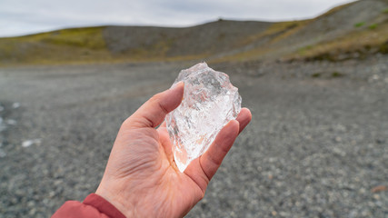 Man holding a piece of ice in Jokulsarlon glacier lagoon formed with melting ice, Iceland