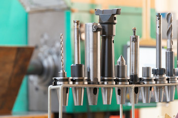 Conical and collet mandrels with cutters and drills on the rack, accessories for the milling machine.