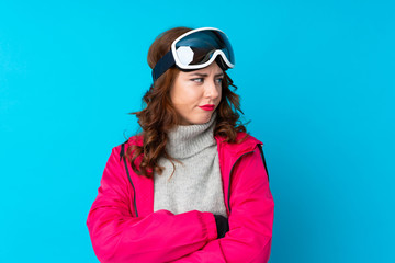 Skier woman with snowboarding glasses over isolated blue wall thinking an idea