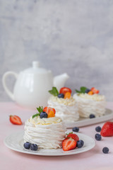Pavlova meringue cake with fresh berries on pink background
