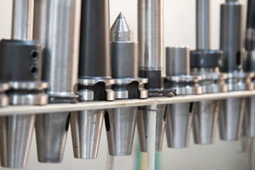 Conical and collet mandrels with cutters and drills on the rack, accessories for the milling machine. - obrazy, fototapety, plakaty