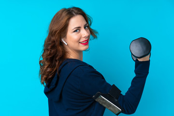 Young sport woman over isolated blue background making weightlifting