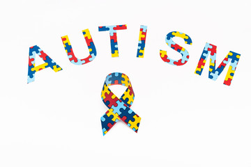 High angle view of Autism puzzle lettering and awareness ribbon isolated on white