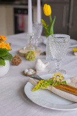 Easter festive spring table setting decoration, eggs in nest, fresh yellow tulips, marshmallows, selective focus