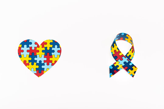 Top view of puzzle heart and awareness ribbon isolated on white, autism concept