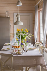 Easter festive spring table setting decoration, eggs in nest, fresh yellow tulips, marshmallows, selective focus
