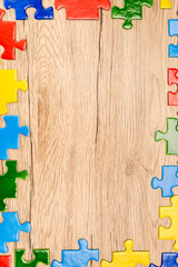 Top view of colorful pieces of puzzle on wooden background, autism concept