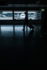 Fototapeta premium Airport rush: people with their suitcases walking along a corridor (motion blurred image; color toned image)