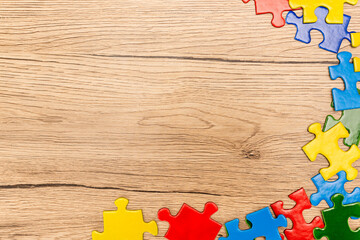 Top view of multicolored pieces of puzzle on wooden background, autism concept