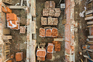 Aerial view of building site for future brick house, concrete foundation floor and stacks of yellow...