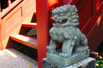 Stone lion sculpture placed beside the stairs up the Thai house