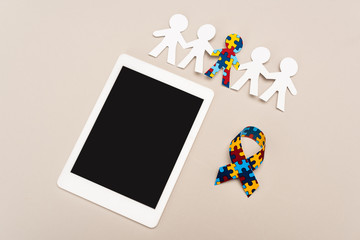 High angle view of awareness ribbon, digital tablet and special kid with autism among another on white