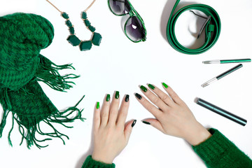 Fashionable green manicure on long nails and women's accessories in various shades of green on a...