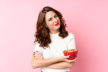 Young Russian woman over isolated pink background holding a bowl of cereals