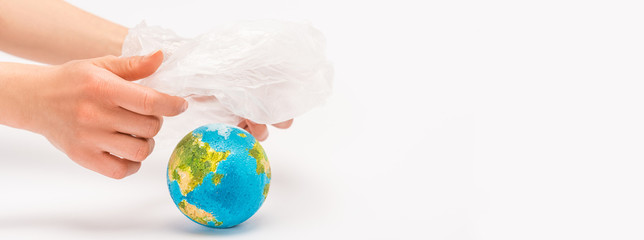 Cropped view of woman holding plastic bag above globe on white, global warming concept