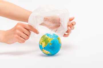 Partial view of woman holding plastic bag above globe on white, global warming concept