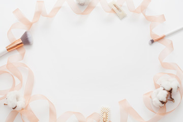Wedding background for inscriptions, decors with a delicate ribbon, cotton flower, makeup brushes, with copy space. The concept of the wedding or gentle backgrounds for themed makeup or facial care.