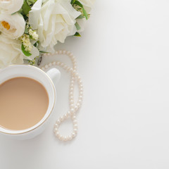 White background with a wedding bouquet, pearl beads and a Cup of coffee with milk, with copy space. Concept backgrounds for wedding texts or romantic texts.