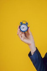 a retro watch held in a lady's palm, on a yellow background