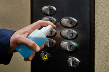 man disinfecting the buttons of an elevator
