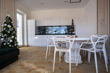 Interior of modern spacious kitchen with white walls, decorative wooden elements, contemporary furniture and big soft couch.