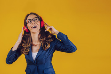 The high-spirited European woman looks at the open space, feels distracted and satisfied, listens to the broadcast with modern headphones connected to the phone, checks the sound.