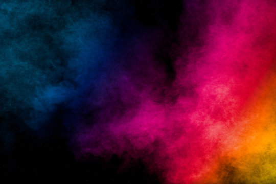 Multi colored particles explosion on black background.Colorful dust splash on dark background.