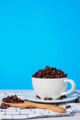 Coffee mugs and coffee beans on a wooden table with a blue backdrop