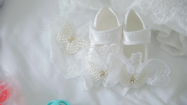 little white shoes with pearls lying on the bed for baby girl