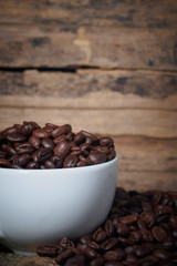 Fototapeta premium Coffee beans in a cup on a wooden table