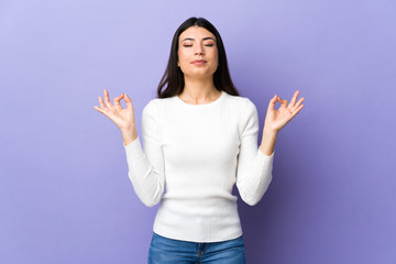 Fototapeta premium Young brunette woman over isolated purple background in zen pose