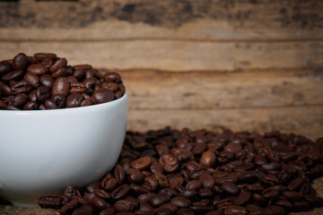 Fototapeta premium Coffee beans in a cup on a wooden table