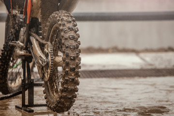 Cross-bike washing after the competition. Washing dirty wheel of motorcycle after the race. Detail...