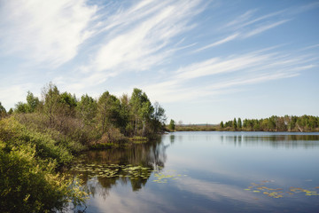 Fototapeta na wymiar Dynamic clouds over a calm rural lake. Country Life Concept